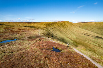Epic view of hiker on peak of the Brecon Beacons National Park, near Abercynafon and Talybont Reservoir