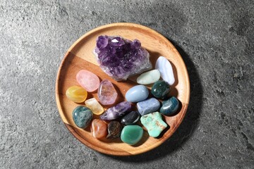 Different beautiful gemstones on grey table, top view