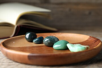 Different beautiful gemstones and book on table, closeup