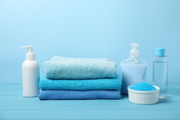 Fresh terry towels and personal hygiene products on light blue background. Space for text