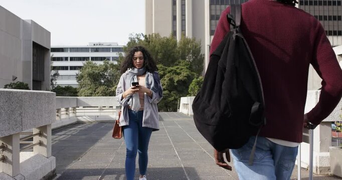 Diverse couple crossing skybridge texting, spotting each other with suitcase, greeting and hugging