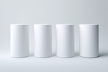 Four plain white cylinders on a light gray background