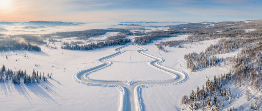 Aerial view of snowy landscape with road shaped like Christmas tree in winter forest - Powered by Adobe