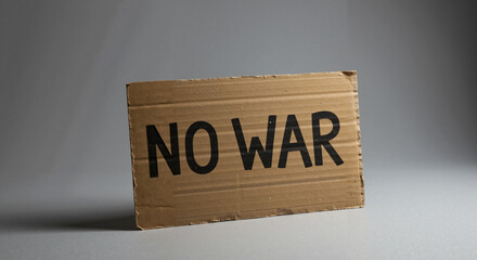 Cardboard sign reading "No War" on neutral background  