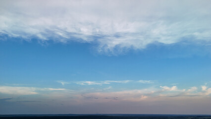 Vast blue sky with soft clouds creating a serene landscape at sunset. Ideal for nature-themed projects or backgrounds, evoking tranquility and openness.