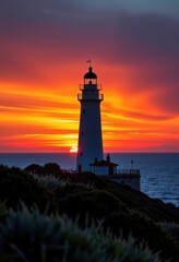Naklejka premium Majestic lighthouse silhouetted against a vibrant sunrise over the North Sea, List, Sylt, vacation, tower, scenic