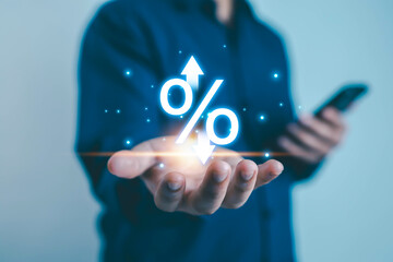 Businessman holding glowing percentage icon with up and down arrows, symbolizing interest rates,...