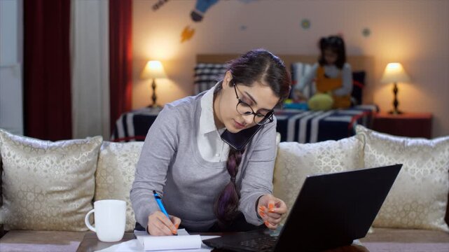 An attractive businesswoman is talking to a client while working on a laptop - client call  nerd  computer programmer  IT professional  work from home. Female entrepreneur wearing eyeglasses - maki...