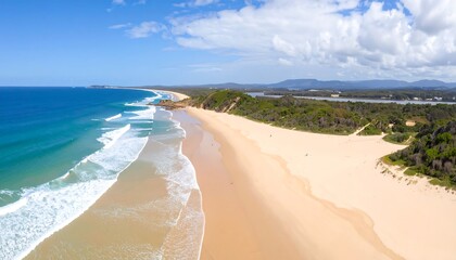 Aerial view of sandy beach meeting turquoise ocean under bright sunny sky