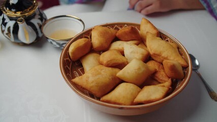 Hand taking baursak from basket of traditional pastries