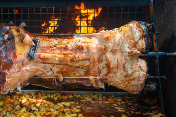 Chef Hands cutting whole grilled pork for steaks with knife. Pig grilled traditional coal and fire. The little pig is roasted whole on an open fire. Pig on the spit