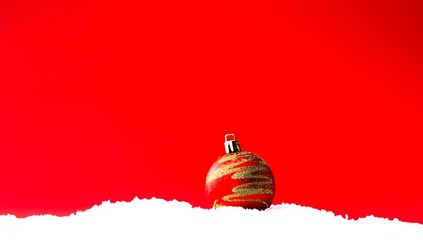 Red Christmas Ornament on Snowy Surface Against Bright Red Background