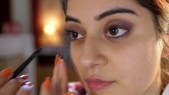 An attractive Indian female is applying Kajal - skincare  eye makeup  eye closeup  fair skin  Asian  pink lipstick  beautiful eyes  model. A pretty Indian lady is getting ready for work - urban lif...