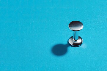 Chrome push pin on vibrant blue background