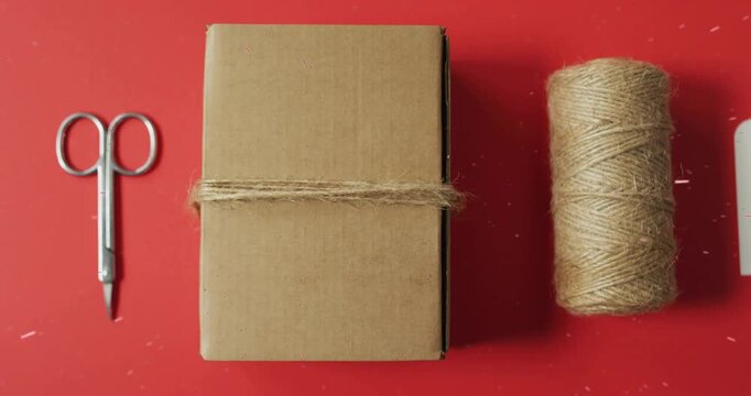 Flat-lay featuring spool sliding toward box starting gift tag entering and sprig completing wrap