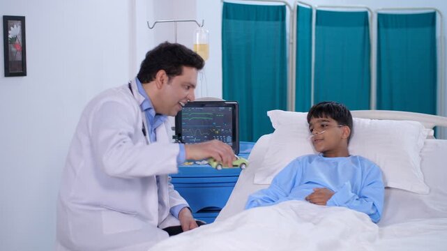 A pediatrician is talking to a child admitted to the hospital - friendly doctor  hospital room  private hospital room  Ayushman Bharat . A sick boy with an oxygen nasal tube is playing with a toy c...