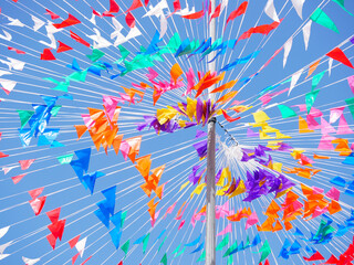 Fototapeta premium Colorful flags and streamers create a vibrant display against a clear blue sky.