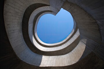 Spiraling concrete ramps open to a clear blue sky