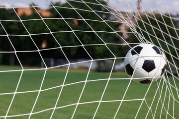 Hitting soccer ball in net outdoors, closeup. Football game