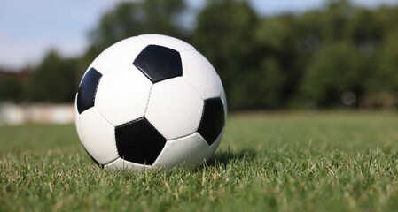 Soccer ball on green grass outdoors, space for text. Football game