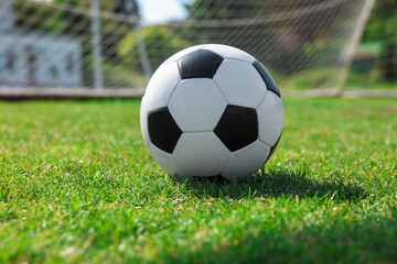 Fototapeta premium Soccer ball on green grass outdoors. Football game