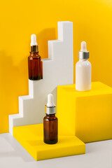 Glass cosmetic bottle with oil or serum for skin care on special podium on yellow background. Natural skin care concept.