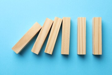 Risk. Wooden blocks falling on light blue background, flat lay with space for text