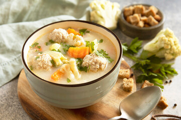 Hearty meatball soup with vegetables and herbs for a cozy meal.