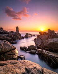 Serene sunrise over coastal rocks, smooth water
