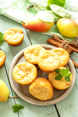 Freshly baked pear muffins with cinnamon and mint on rustic wooden table