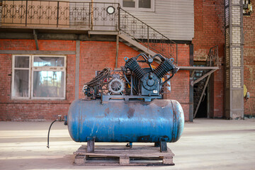 A large blue industrial compressor stands in the middle of the hangar on a wooden pallet. High...
