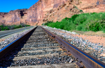 Railroad at the bottom of a canyon next to Layered Geological Formations of Red Rocks. USA