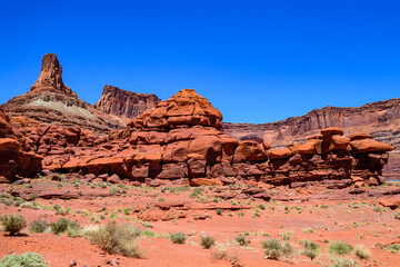 Dirt road at the bottom of the canyon among the layered geological formations of red rocks in...