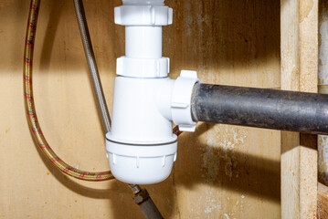 A new plumbing trap under the kitchen sink and old drain pipes.
