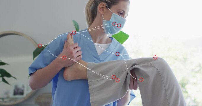 Physical therapist wearing blue scrubs and mask bending right knee, mobilizing ankle joint on table