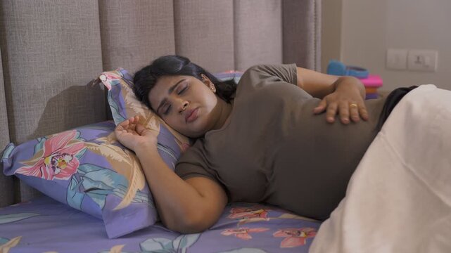 Pregnant lady feeling unwell lying in bed - sleeping disorder  disturbed sleep  troubled sleep  sleep apnea . A young expectant mother disturbed with pain in the belly - difficult pregnancy  health...