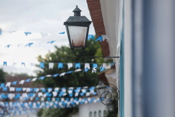 Rua de cidade hist&oacute;rica brasileira decorada com bandeirinhas azuis, destacando arquitetura colonial e atmosfera festiva.