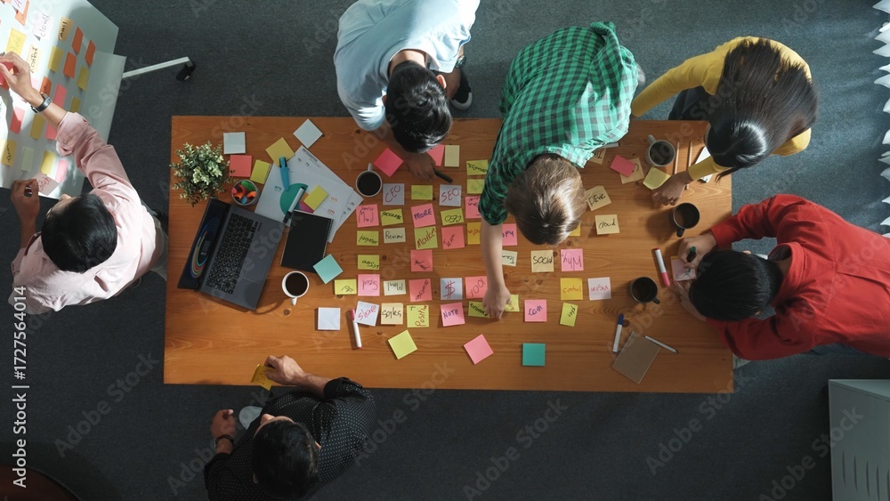 Poster top view of skilled business people discuss plan at meeting room while writing idea at sticky notes 