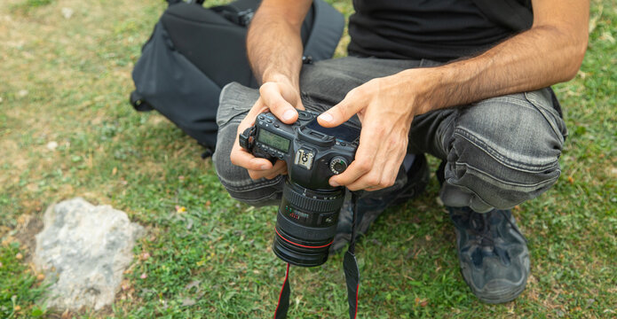 Photographer holding a digital camera taking pictures in nature. - Powered by Adobe