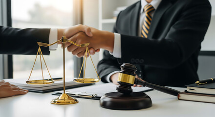 Attorneys shaking hands with a gavel and scales of justice at a desk