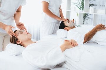 Obraz premium Serene modern daylight ambiance of spa salon, couple customer indulges in rejuvenating with facial skincare mask. Facial skin treatment and beauty cosmetology procedure for face. Quiescent