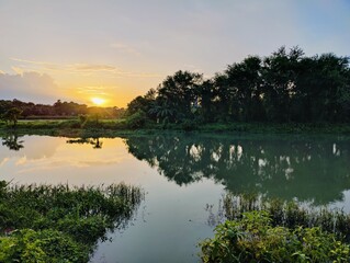Tranquil sunset over a reflective lake surrounded by verdant forest scenery