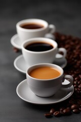 Fototapeta premium Three cups of coffee with different brew intensities and coffee beans on dark background