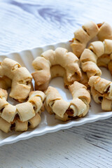 Close-Up of U-Shaped Apple Cookies on a Rectangular Plate on a White Wooden Surface