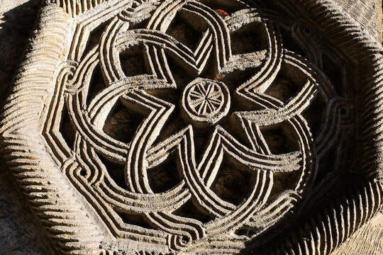 Armenian medieval stone carving exhibiting intricate everlasting knotwork and geometric rosette patterns, symbolizing eternity and cultural heritage in ancient architecture