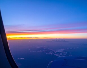 Airplane window view of vibrant sunset over clouds