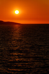 Vibrant sunset over calm ocean waves at serene coastal location