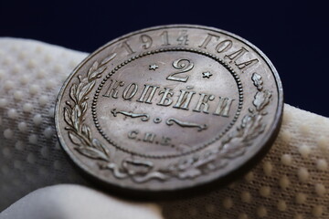 A close-up of a vintage 1914 two kopecks coin, featuring intricate designs and inscriptions, held...