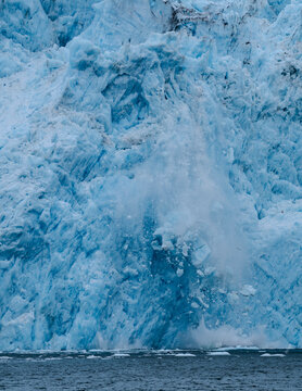 Close-up of the collapse of a massive segment of ice of the Aiakal Glacier as it tumbles to the sea