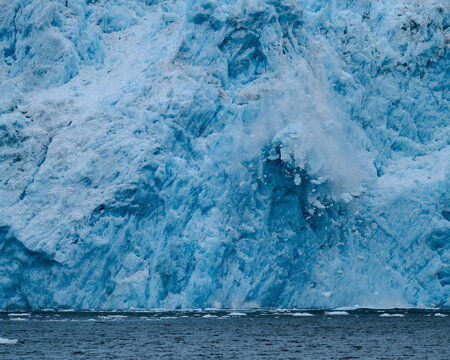 Close-up of the collapse of a massive segment of ice of the Aiakal Glacier as it tumbles to the sea